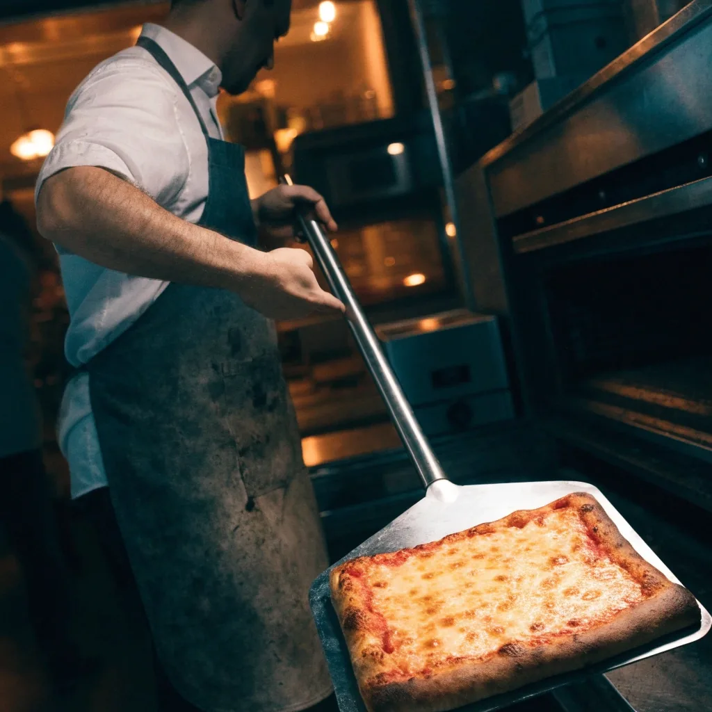 Thin-crust pizza on the pass counter under hard overhead light
